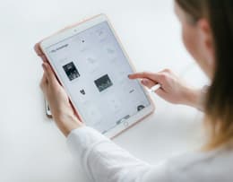 A person using an iPad with the screen visible.